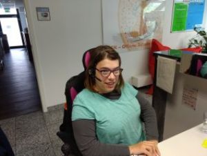SAbrina Michael am Arbeitsplatz sitzend mit Headset