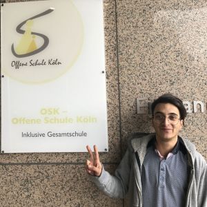Mohammad freut sich vor dem Schulgebaeude